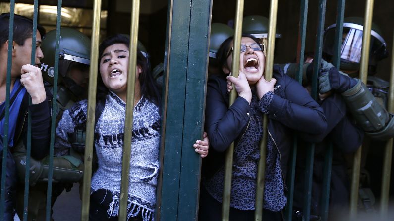 University students in Santiago, Chile, cling to a fence at the Education Ministry building while protesting a financial crisis at their school on Friday, September 12.