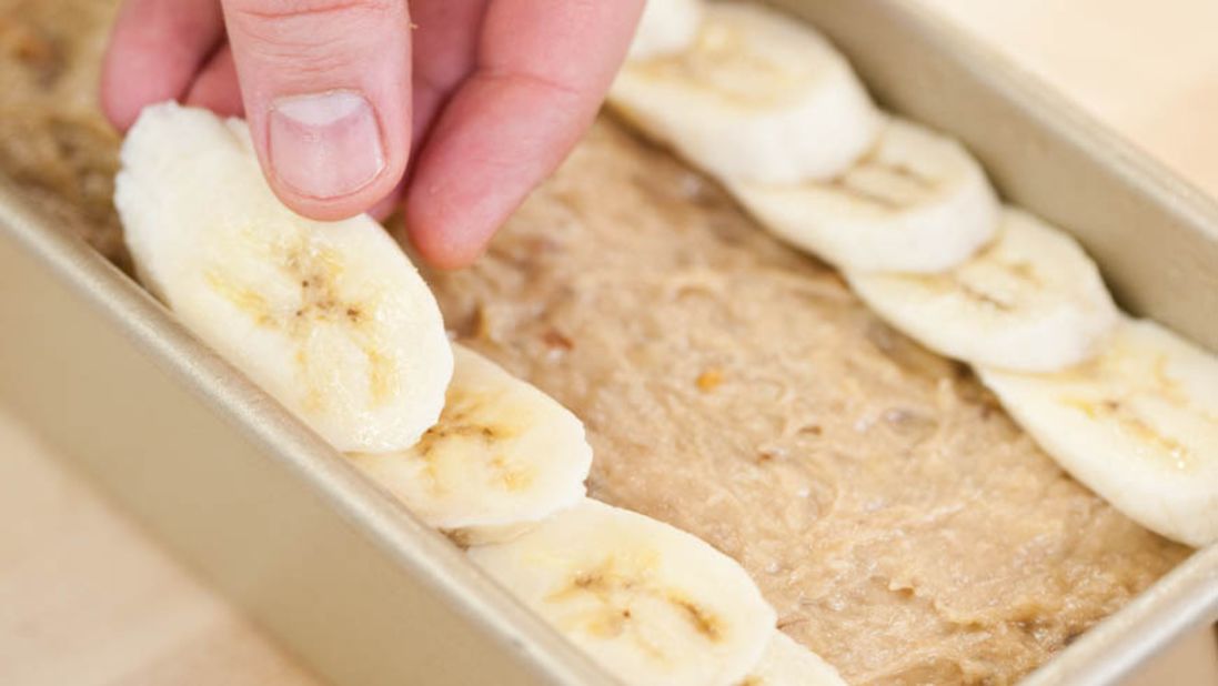 9. For topping, peel 1 large, very ripe banana and cut on bias into 1/4-inch-thick slices. Shingle banana slices on loaf in 2 rows, leaving 1 1/2-inch-wide space down center. Sprinkle 2 teaspoons granulated sugar evenly over loaf.