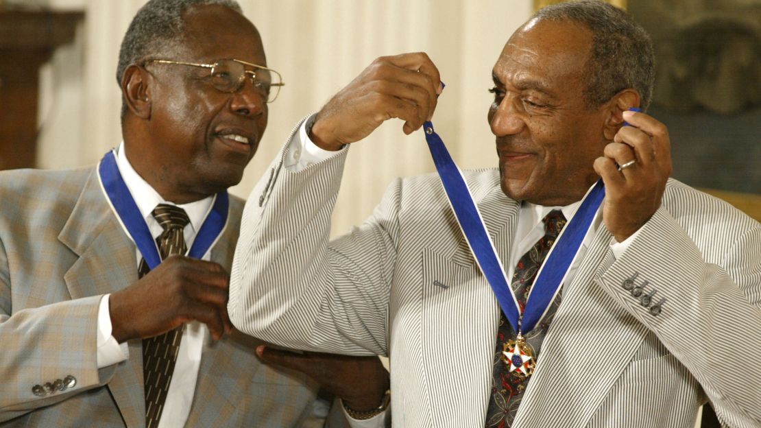 Comedian Bill Cosby jokes with baseball great Hank Aaron after both received the Presidential Medal of Freedom from President George W. Bush at the White House in 2002.