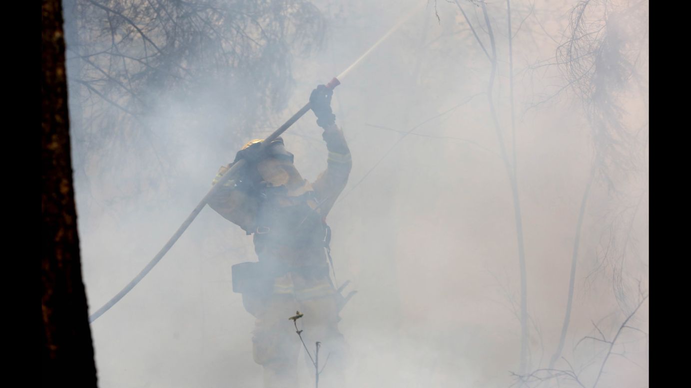 A firefighter waters down a tree as flames approach a containment line near Fresh Pond, California, on September 18.