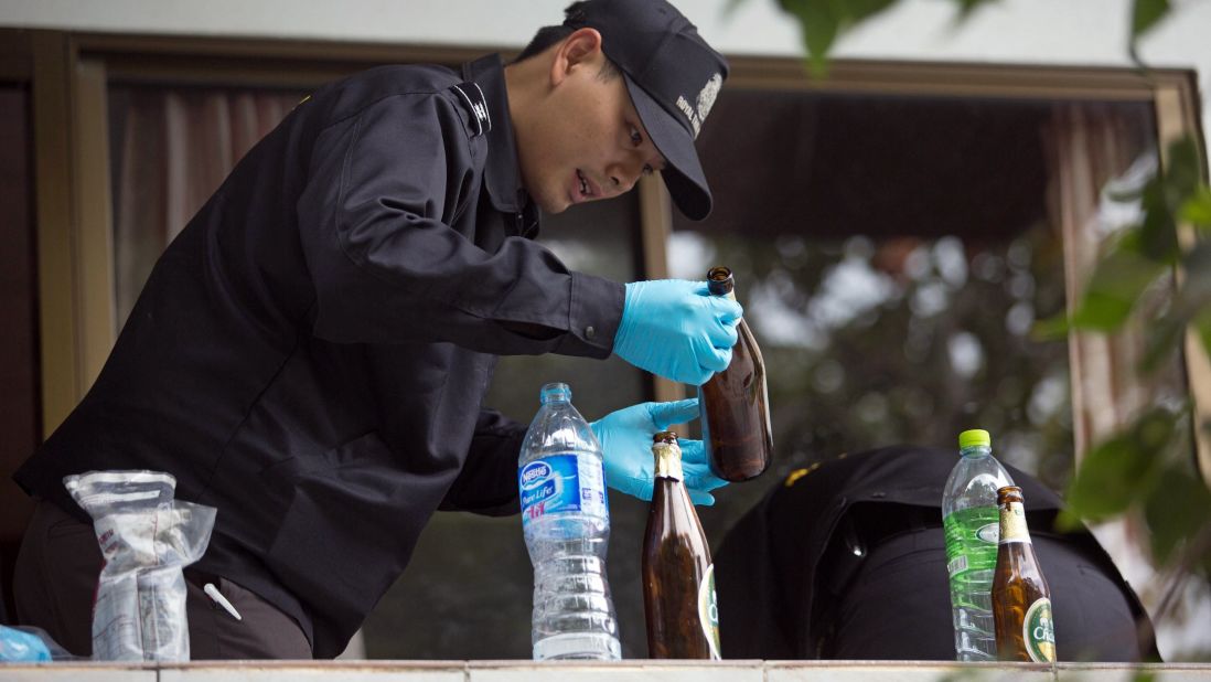 A forensic investigator examines a bottle at a hotel room close to where the couple was found.