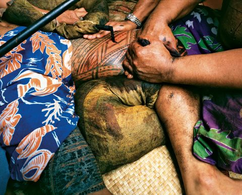 This photograph, taken by Mark Adams in 1980, captures the bloody and painful process of customary tattoo among Samoan men. It involves excruciating pain, said to be the equivalent of childbirth in women.