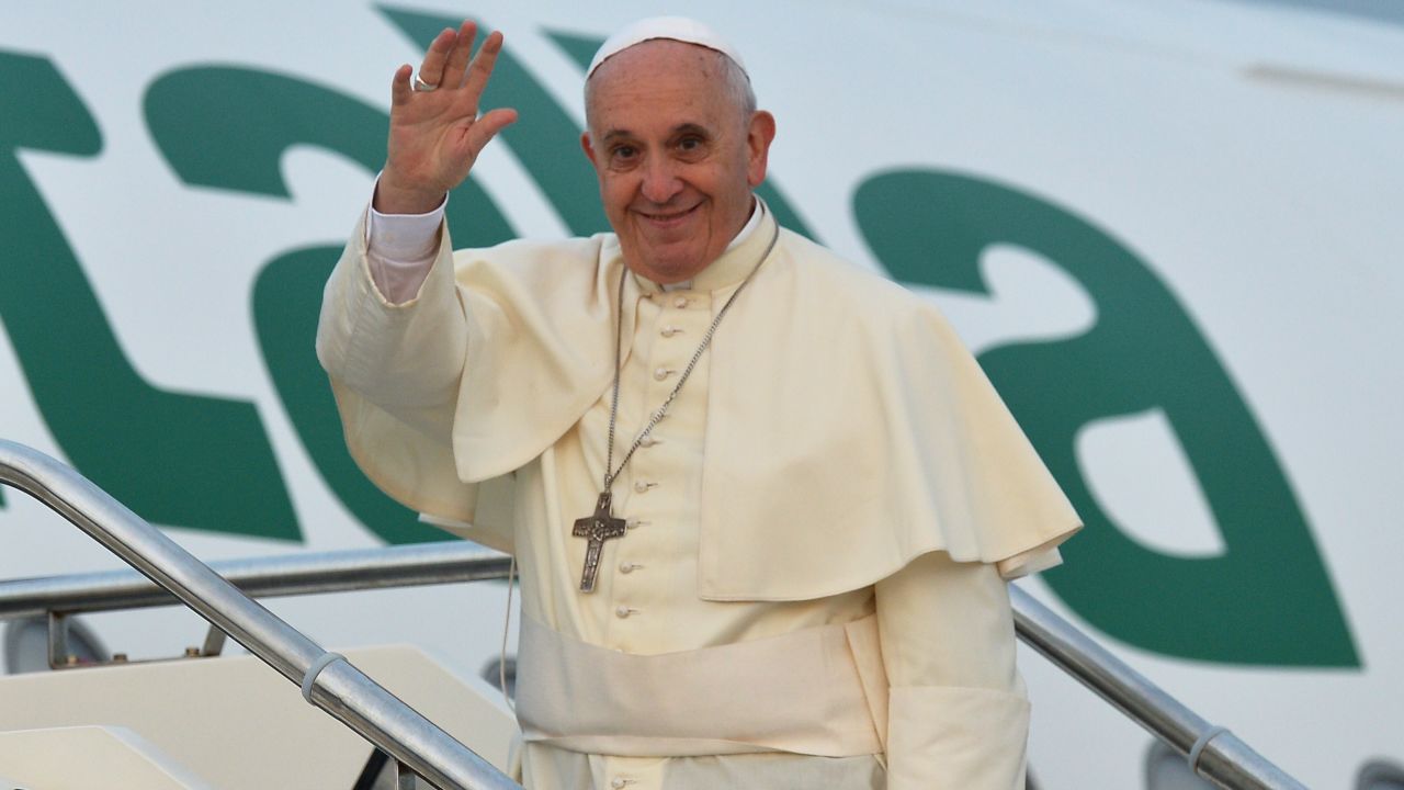 Pope Francis waves from the top of the stairs leading to the plane that will carry him to Tirana, on September 21, 2014 at Rome's Fiumicino international airport