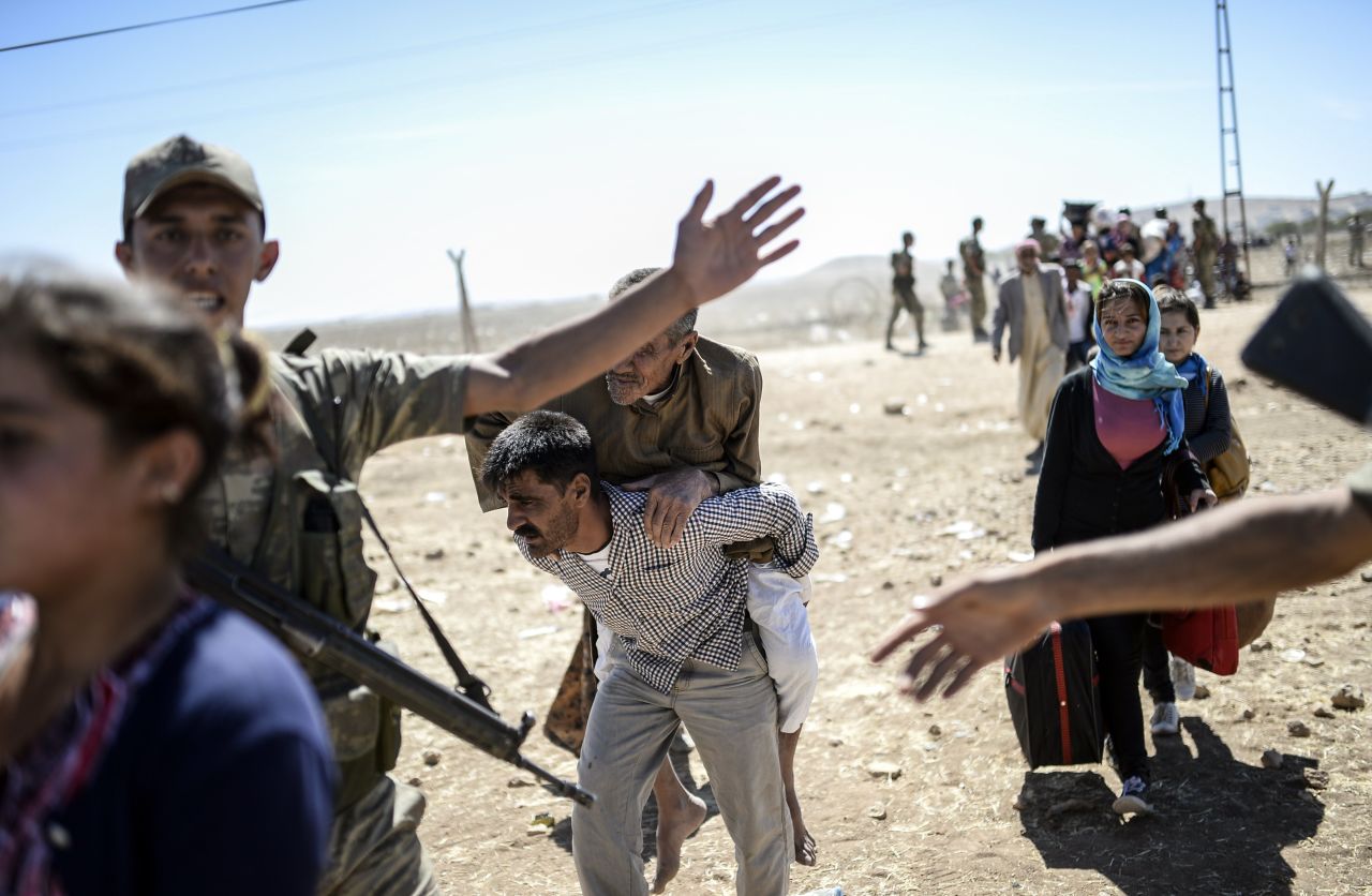 A elderly man is carried after crossing the Syria-Turkey border near Suruc on Saturday, September 20.