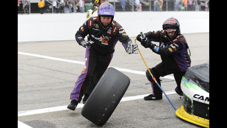 Two members of Denny Hamlin's pit crew change a tire during the NASCAR Sprint Cup race in Loudon, New Hampshire, on Sunday, September 21.