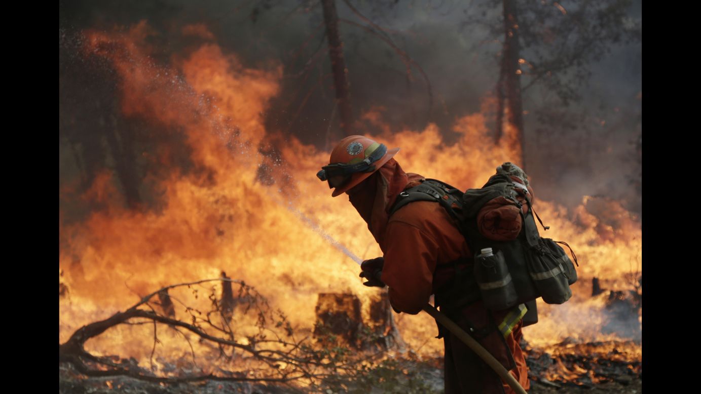 A firefighter hoses down hot spots during a controlled burn to fight the King Fire near Placerville, California, on Monday, September 22. The King Fire is one of 10 wildfires raging across California.