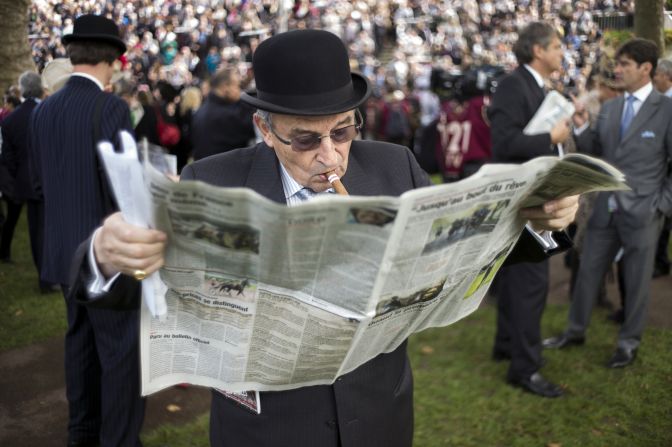 An elderly punter checks the newspaper form on race day at the Prix de l'Arc de Triomphe.