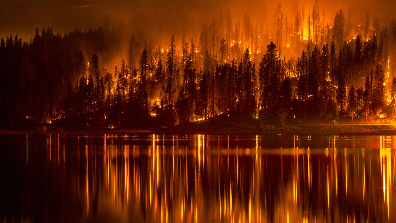 There's not a direct link between climate change and wildfires, exactly. But many scientists believe the increase in wildfires in the Western United States is partly the result of tinder-dry forests parched by warming temperatures. This photo shows a wildfire as it approaches the shore of Bass Lake, California, in mid-September. 
