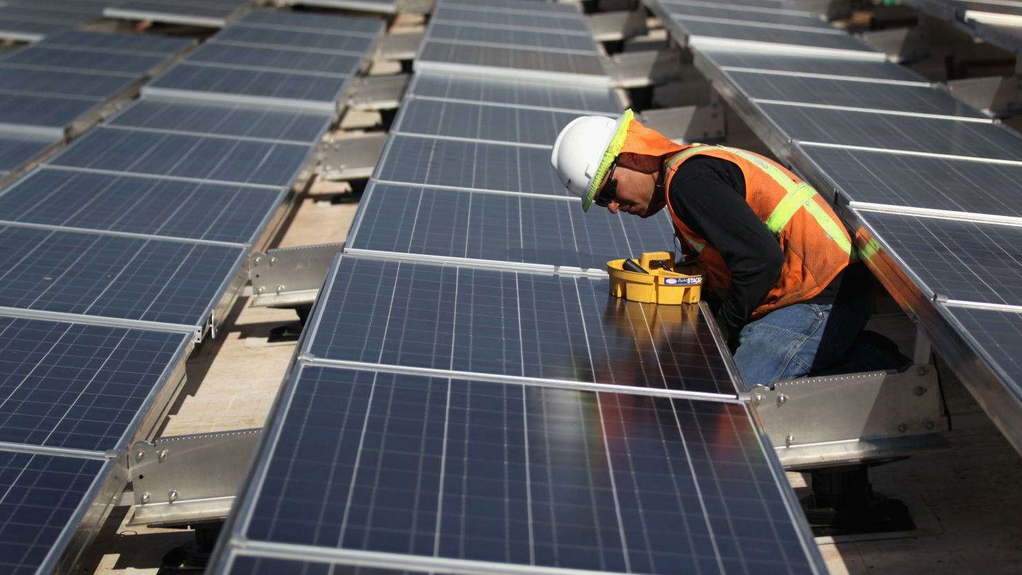  A worker finishes installing solar panels on top of a building.