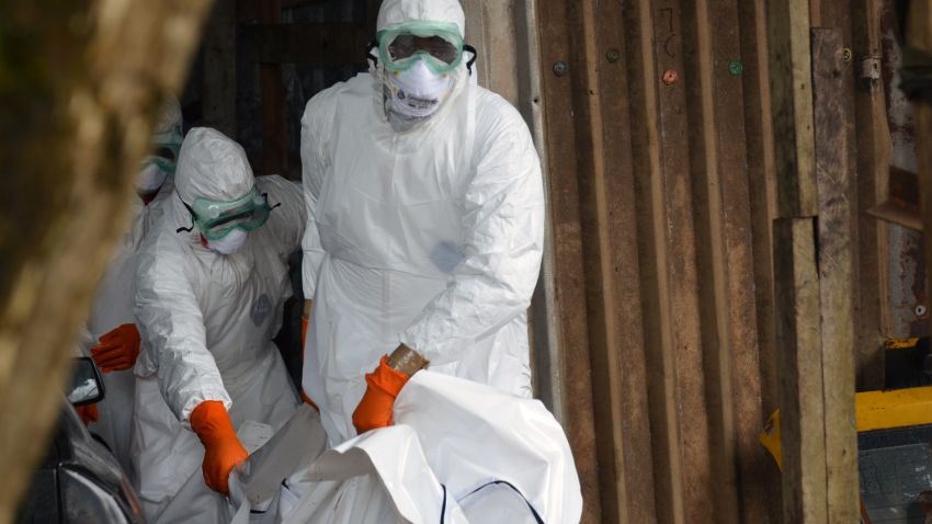 Liberian Red Cross health workers wearing protective suits carry the body of a victim of the Ebola virus out of a garage on September 10, 2014 in a district of Monrovia.