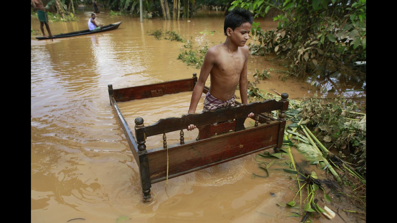 A boy carries a bed frame through floodwaters in the Indian village of Krishnai on Wednesday, September 24. Landslides and flash floods triggered by two days of heavy rain killed dozens of people in India's remote northeast.