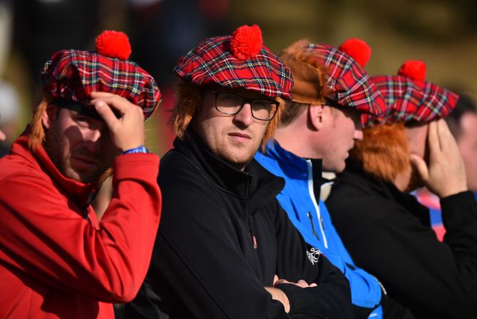 Spectators wearing Tartan caps complete with ginger wigs watch play during day one at Gleneagles. 