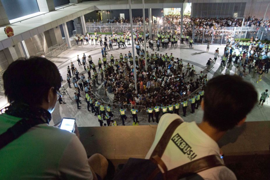 People watch from on high as pro-democracy demonstrators are surrounded by police after storming a courtyard outside Hong Kong's legislative headquarters on Friday, September 26.