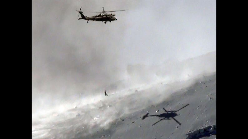 A helicopter lifts a survivor from the ash-covered top of Mount Ontake.