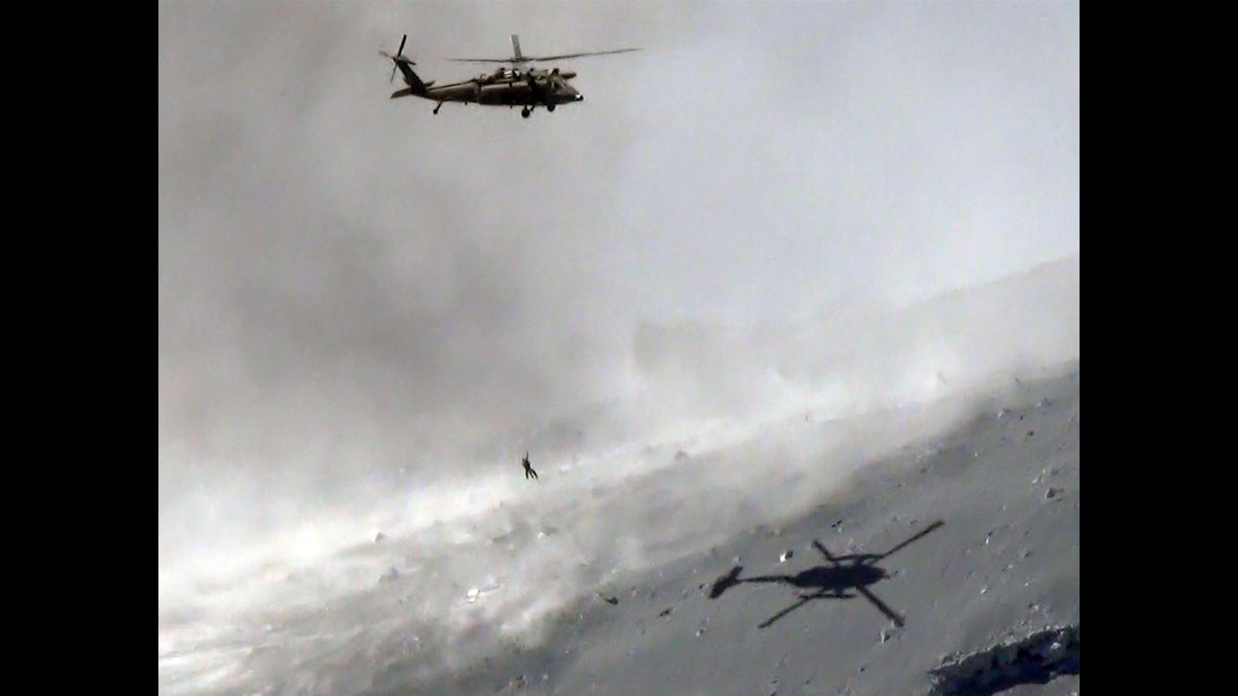 A helicopter lifts a survivor from the ash-covered top of Mount Ontake.