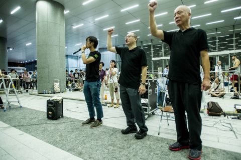 Benny Tai, center, founder of the Occupy Central movement, raises a fist after announcing the group would join the students during a demonstration outside government headquarters in Hong Kong on September 28.
