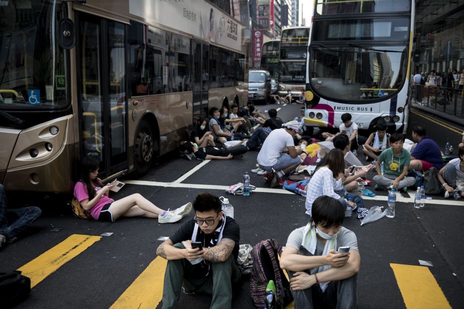 Pro-democracy protesters rest around empty buses as they block Nathan Road in Hong Kong on September 29. Multiple bus routes have been suspended or diverted.