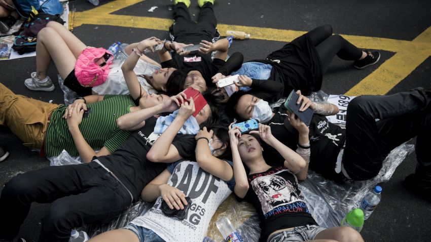 Protesters look at their mobile phones while occupying an intersection in Hong Kong's Mong Kok district on September 29, 2014.