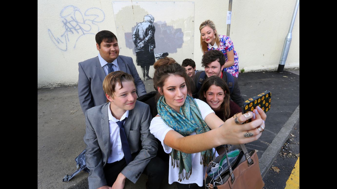 Students in Folkestone, England, take a selfie Tuesday, September 30, in front of a mural created by the street artist Banksy.