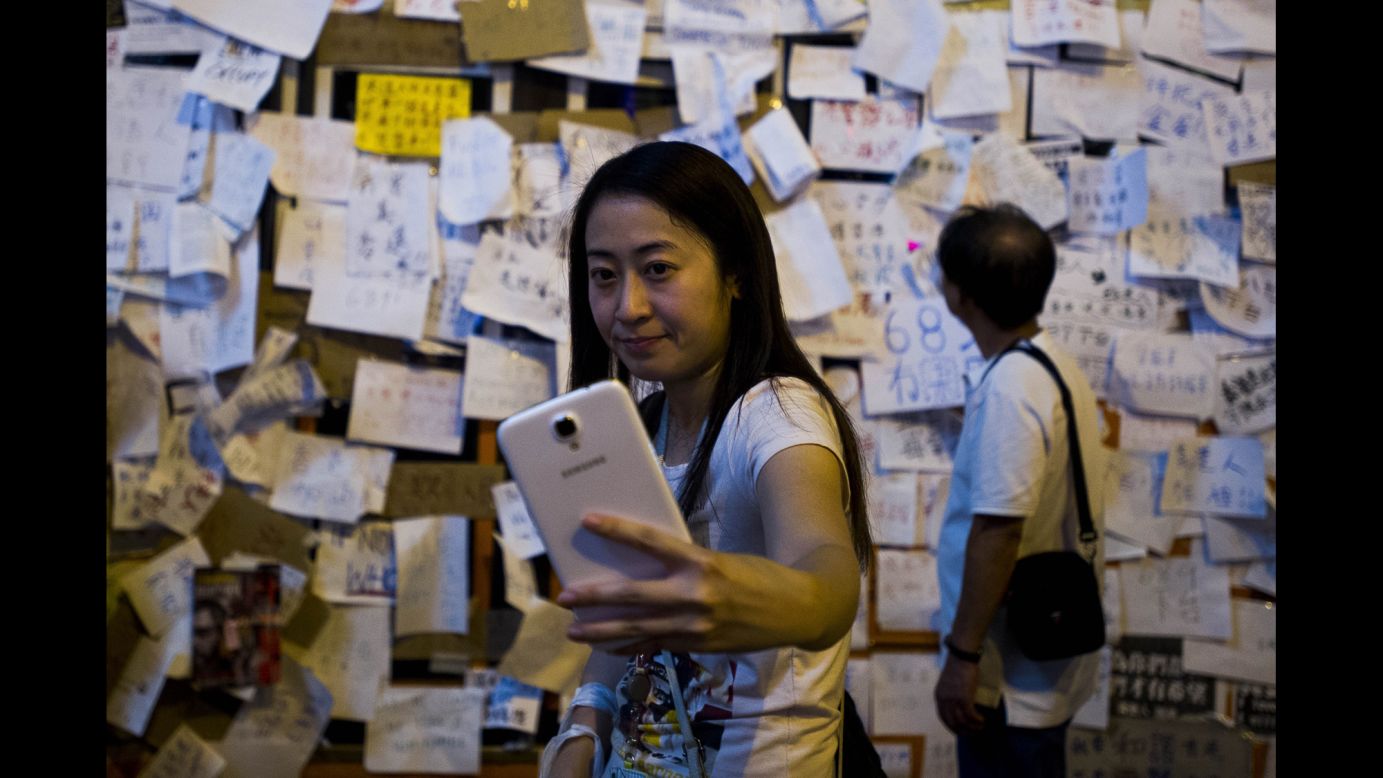 A woman takes a selfie Tuesday, September 30, in front of a bus that is covered with messages of support for the <a href="http://www.cnn.com/2014/09/22/asia/gallery/hong-kong-students-protest/index.html">pro-democracy protests in Hong Kong.</a> Protesters are angry at China's decision to allow only Beijing-vetted candidates to run in the city's elections for chief executive in 2017. They say Beijing has gone back on its pledge to allow universal suffrage in Hong Kong, which was promised "a high degree of autonomy" when it was handed back to China by Britain in 1997.