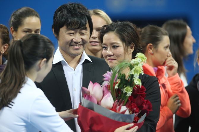 China's two-time grand slam winner Li Na, accompanied by husband Jiang Shan, accepts flowers at a ceremony to mark her retirement.