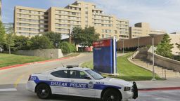 A police car drives past the entrance to the Texas Health Presbyterian Hospital in Dallas, Tuesday, Sept. 30, 2014.  A patient in the hospital is showing signs of the Ebola virus and is being kept in strict isolation with test results pending, hospital officials said Monday. (AP Photo/LM Otero)