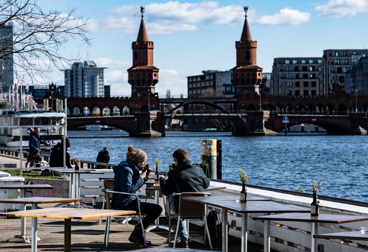 People sit outside at the East Side Gallery in Berlin on March 22.