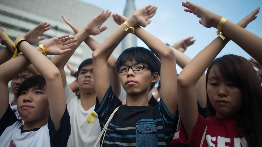 Founder of the student pro-democracy group Scholarism, Joshua Wong, center, stands in silent protest with supporters at the flag-raising ceremony at Golden Bauhinia Square in Hong Kong on October 1. 
