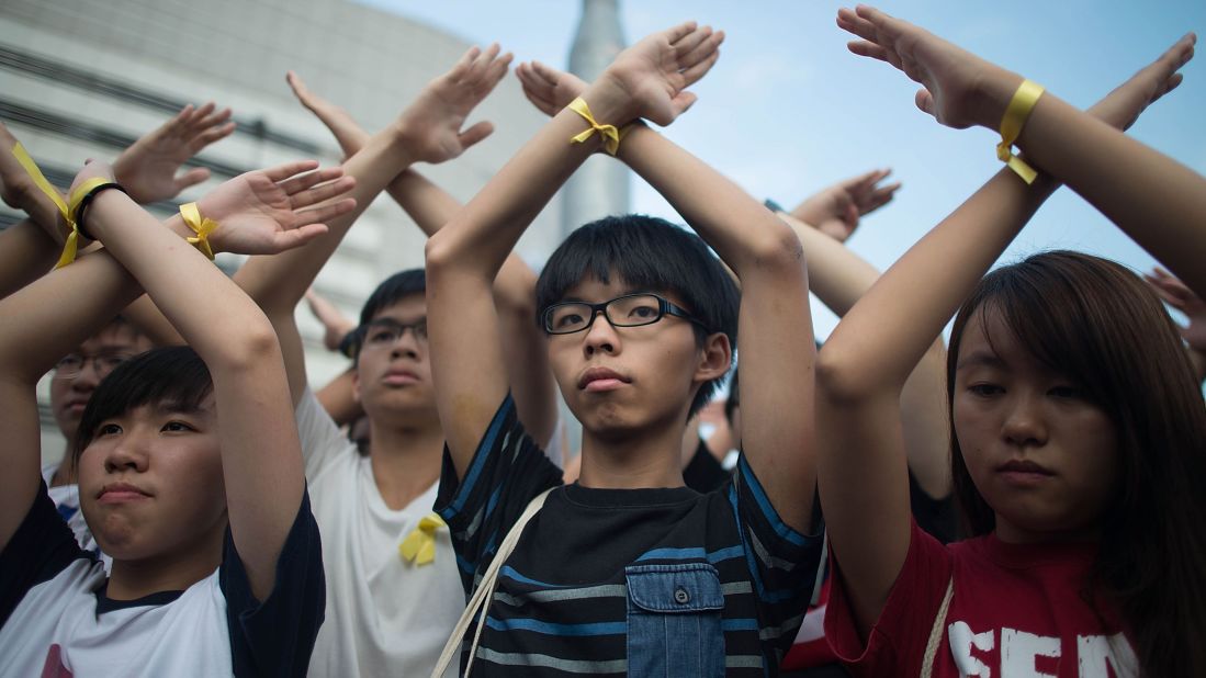 Founder of the student pro-democracy group Scholarism, Joshua Wong, center, stands in silent protest with supporters at the flag-raising ceremony at Golden Bauhinia Square in Hong Kong on October 1.