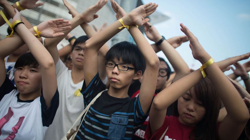 HONG KONG - OCTOBER 01: Student pro-democracy group Scholarism convenor Joshua Wong (C) makes a gesture at the Flag Raising Ceremony at Golden Bauhinia Square on October 1, 2014 in Hong Kong. Thousands of pro democracy supporters continue to occupy the streets surrounding Hong Kong's Financial district. Protest leaders have set an October 1st deadline for their demands to be met and are calling for open elections and the resignation of Hong Kong's Chief Executive Leung Chun-ying. (Photo by Anthony Kwan/Getty Images)