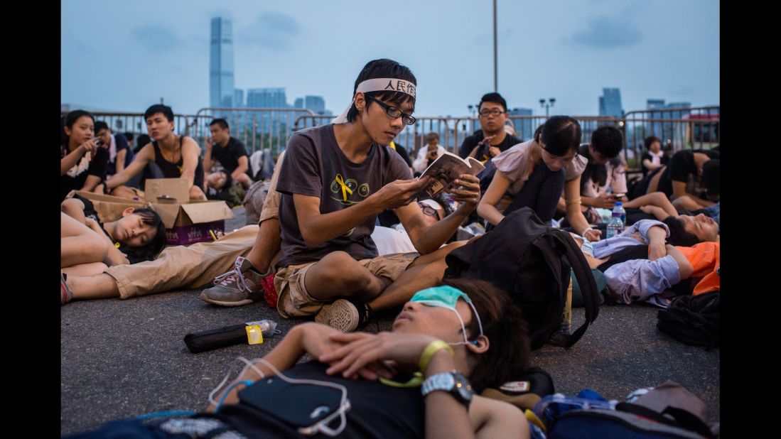 As the sun rises, a protester reads during a sit-in blocking the entrance to the chief executive's office on October 2.