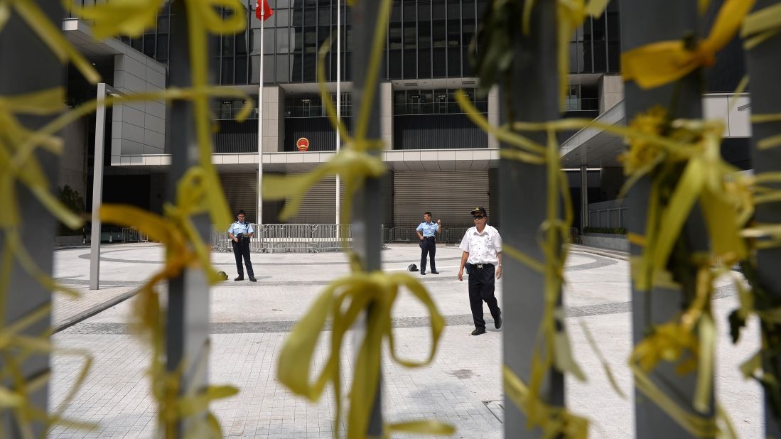 Yellow ribbons, a symbol of the protests in Hong Kong, are tied to a fence as police and security officers stand guard at the government headquarters on October 2.