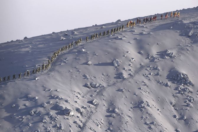 Rescuers walk in line after a search operation near the peak of Japan's Mount Ontake on Wednesday, October 1. Efforts to recover bodies from the erupting volcano have resumed after search teams had been hampered by gas and hot ash shooting into the air. At least 47 people were killed when the volcano erupted over the weekend.