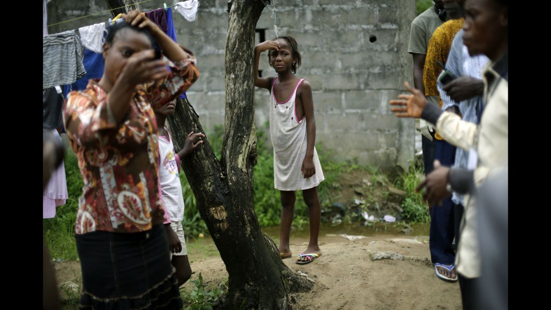 A girl cries as community activists approach her outside her Monrovia home on October 2, 2014, a day after her mother was taken to an Ebola ward.