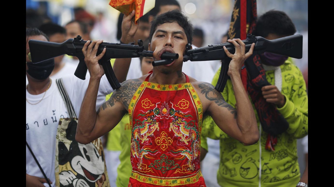 A devotee of the Chinese Bang Neow Shrine, with two plastic guns pierced through his cheeks, takes part in a street procession celebrating the annual vegetarian festival in Phuket, Thailand, on Monday, September 29. The festival, which features face piercing, spirit mediums and strict vegetarianism, celebrates locals' belief that abstinence from meat and various stimulants during the month will help them obtain good health and peace of mind.