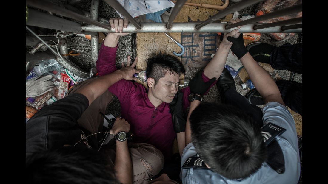 Police try to pry a man from a fence guarded by pro-democracy demonstrators on October 3.