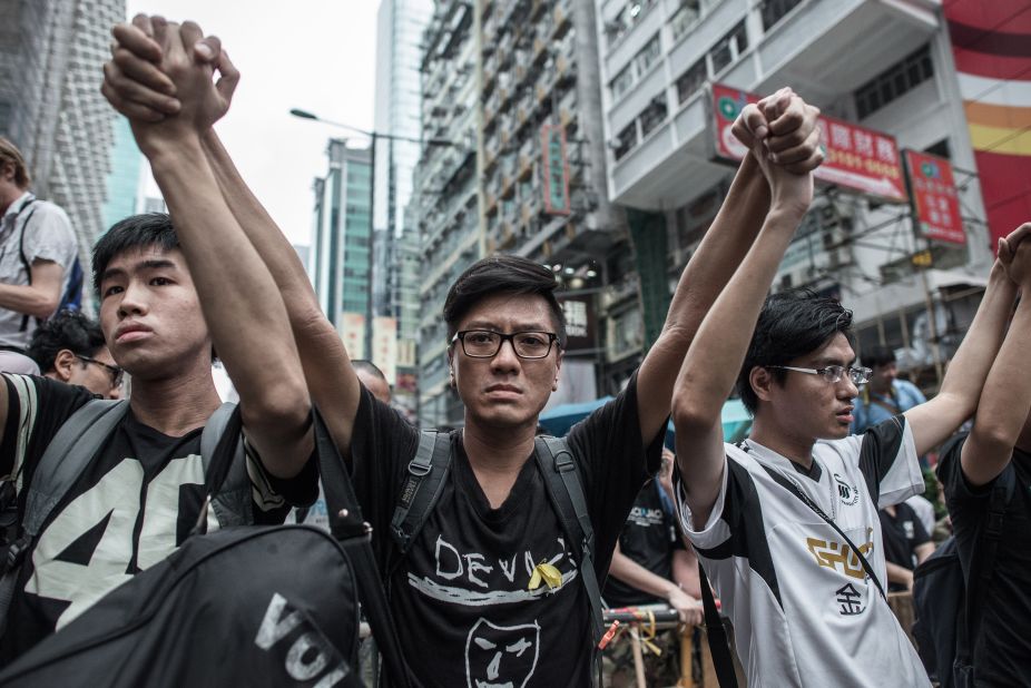 Pro-democracy protesters raise their arms in a sign of nonviolence as they protect a barricade from rival protest groups in the Mong Kok district on October 4.