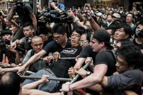 A pro-democracy protester holds on to a barrier as he and others defend a barricade from attacks by rival protest groups in the Mong Kok district on Saturday, October 4.