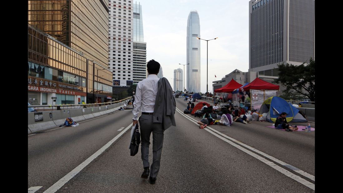 A man walks to work as pro-democracy demonstrators sleep on the road in the occupied areas surrounding the government complex in Hong Kong on October 6.