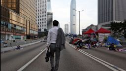 A man walks to work as pro-democracy demonstrators sleep on the road in the occupied areas surrounding the government complex in Hong Kong on Monday, October 6.