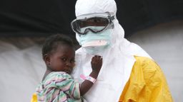 An MSF health worker in protective clothing holds a child suspected of having Ebola in the Paynesville, Liberia, treatment center on October 5.
