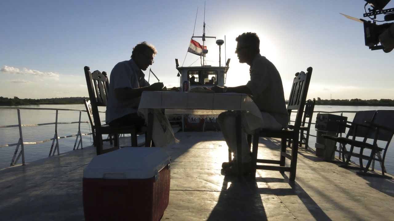 Bourdain and Peter, a German expat, sit down to dinner on the deck of the Cacique II at sunset as it steams up the Paraguay River.