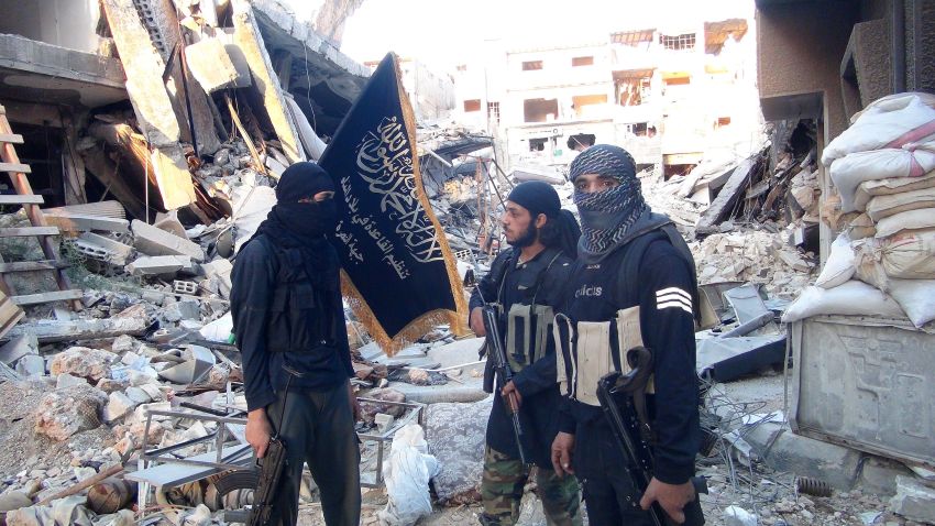 Fighters from the al-Qaeda group in the Levant, Al-Nusra Front, stand among destroyed buildings near the front line with Syrian government solders in Yarmuk Palestinian refugee camp, south of Damascus on September 22, 2014.