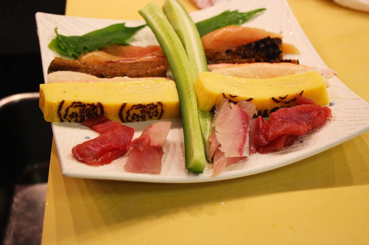 Maki-roll ingredients usually include vegetables and fish. This plate includes cucumber, shiso leaves, omelet and grilled eel that will go inside the roll.