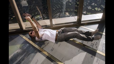 A visitor lies down to take a selfie on the new glass floor of Paris' Eiffel Tower on Friday, October 3. The transparent walkway offers dramatic views 187 feet in the air.