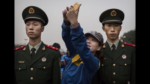 A woman poses for a selfie between two soldiers in Beijing on Wednesday, October 1. It was China's National Day, a holiday that marks the republic's founding.