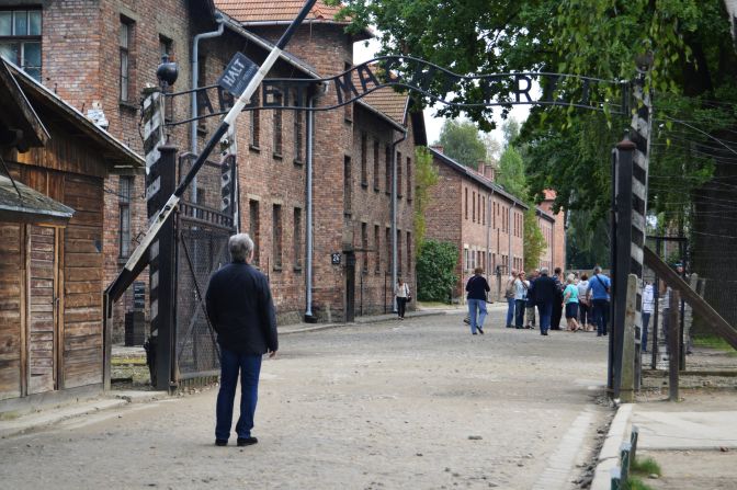 Blitzer stands at the entrance to Auschwitz, where the Nazis had a slogan, "arbeit macht frei," that translates to "work will set you free."