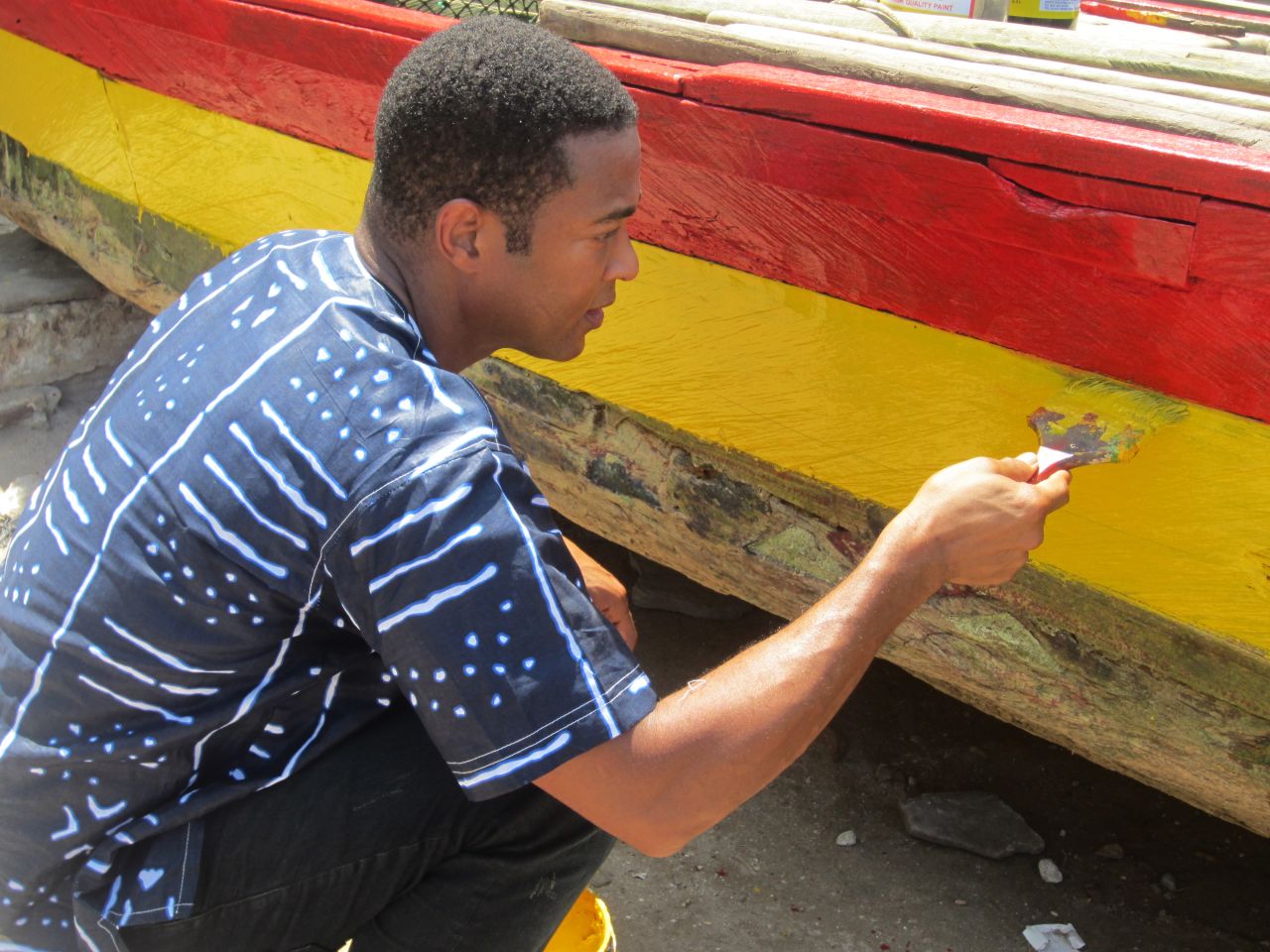 While visiting Elmina Beach, Lemon noticed an elderly fisherman painting his boat. He jumped in to help.