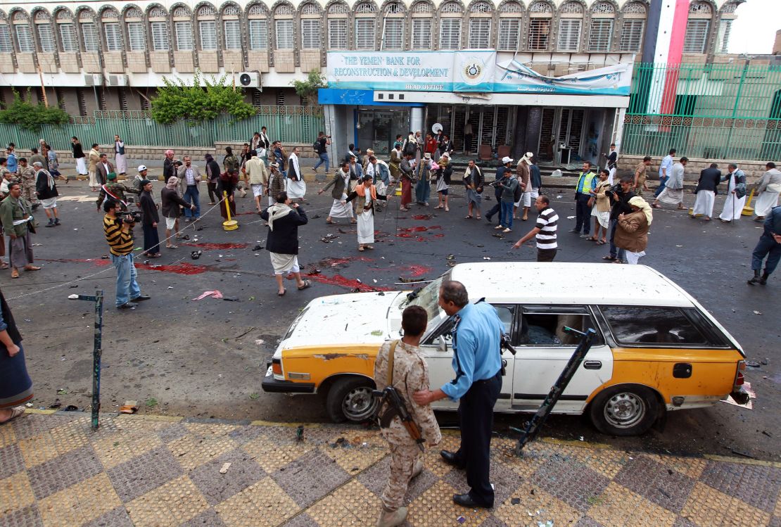  Yemeni security forces and Shiite Huthi militiamen stand next to pools of blood on the ground after a powerful suicide bombing rocked the Yemeni capital Sanaa on October 9, 2014.