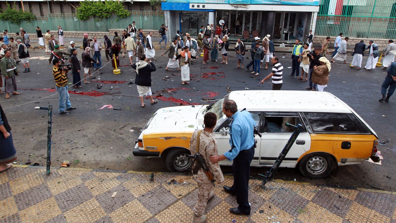 Yemeni security forces and Shiite Huthi militiamen stand next to pools of blood on the ground after a powerful suicide bombing rocked the Yemeni capital Sanaa on October 9, 2014.